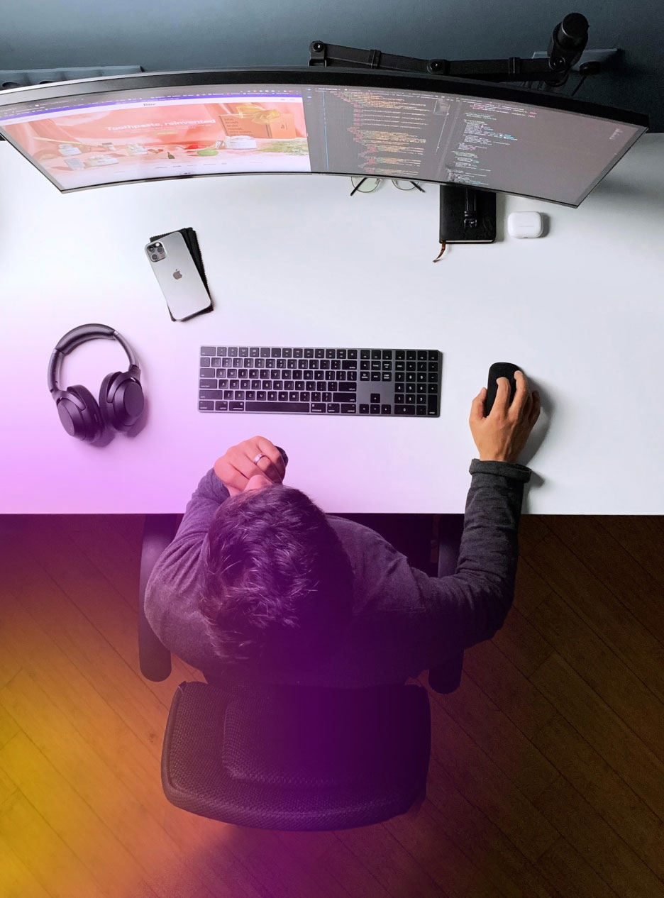 Person Working on Computer 1 Overhead view of a person at a clean desk using a curved ultrawide monitor, keyboard, mouse, headphones, and smartphone.